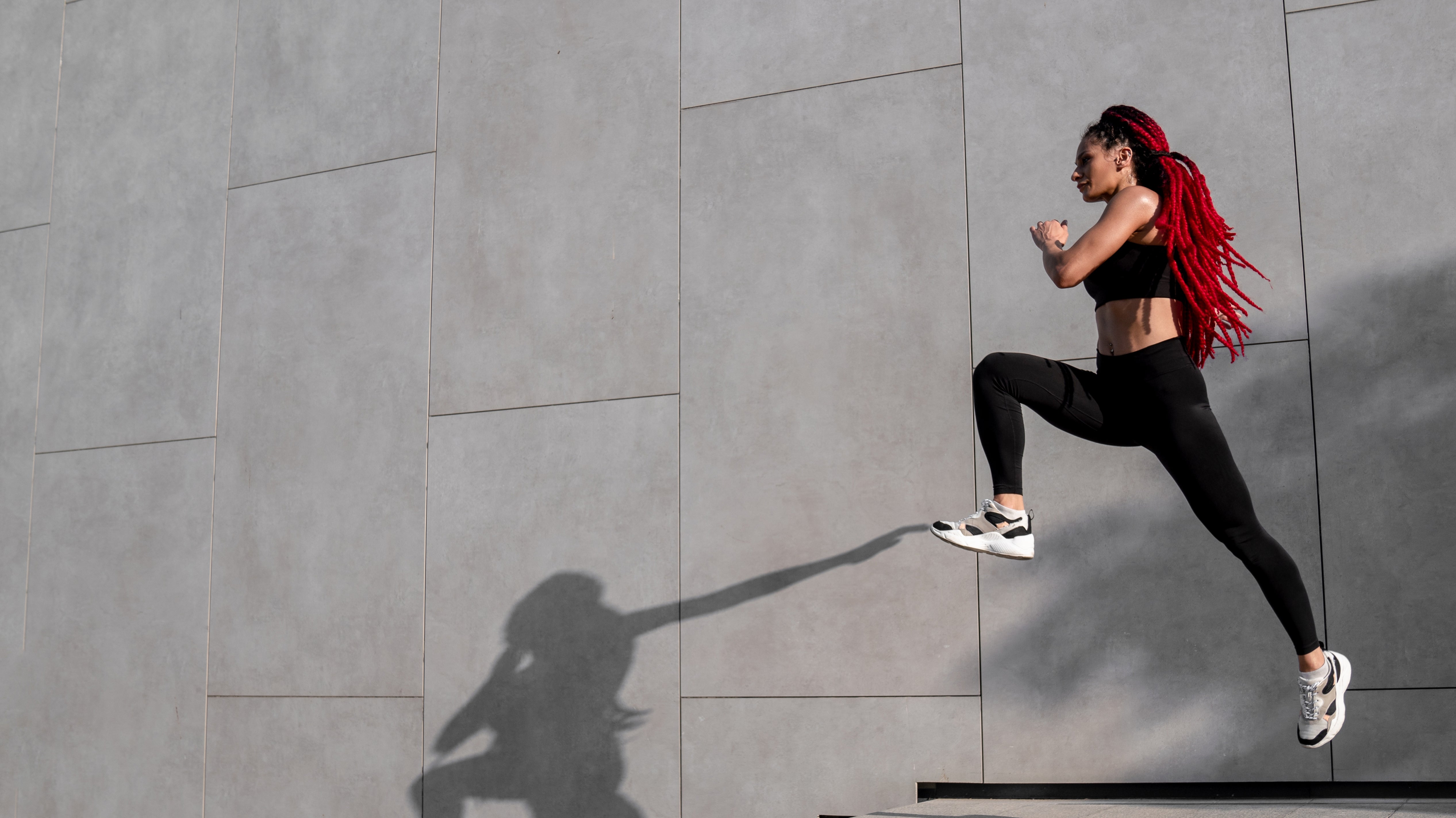 A woman jogging in front of a wall.